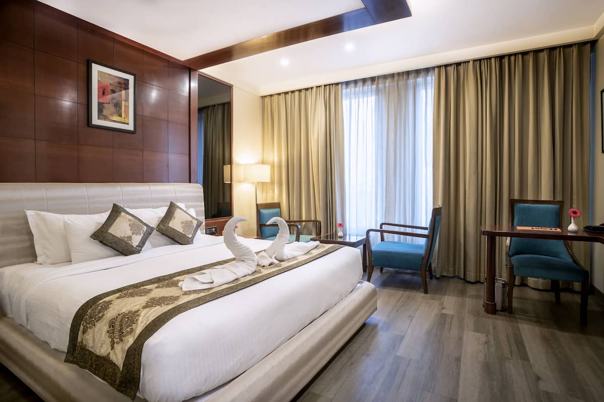 Een hotelkamer met een groot bed, een bureau, een stoel en een raam met gordijnen.
