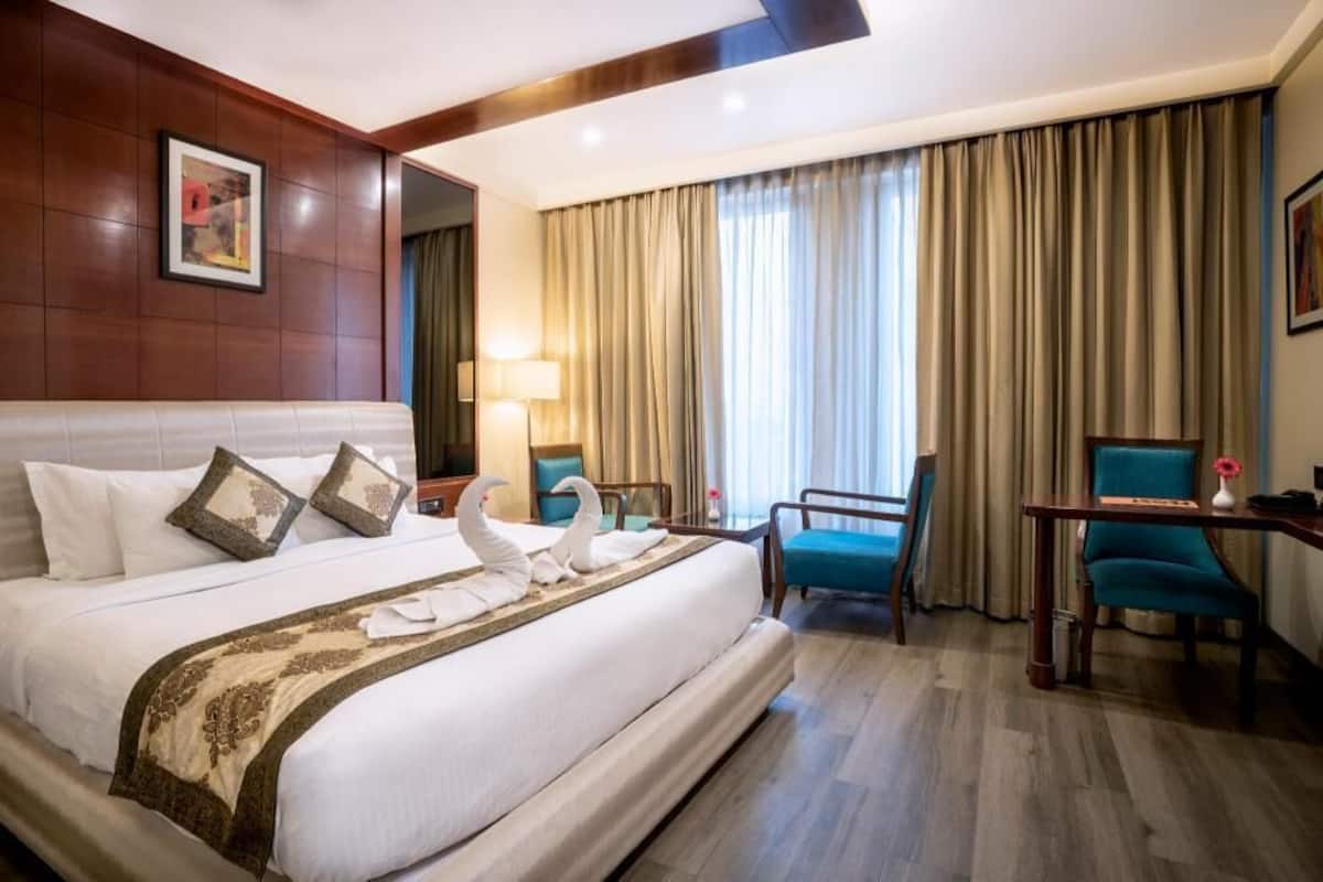Een hotelkamer met een groot bed, een bureau, een stoel en een raam met gordijnen.