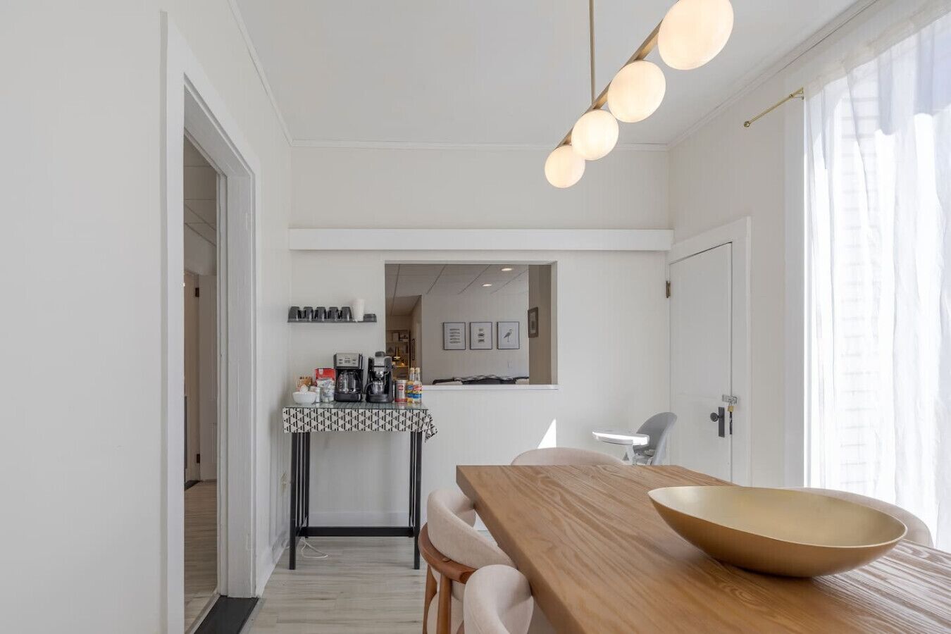Une cuisine moderne avec une table à manger en bois, un coin café et une vue sur l’espace de vie.
