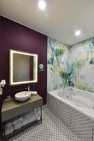 Un baño con tocador, lavamanos, espejo y bañera.