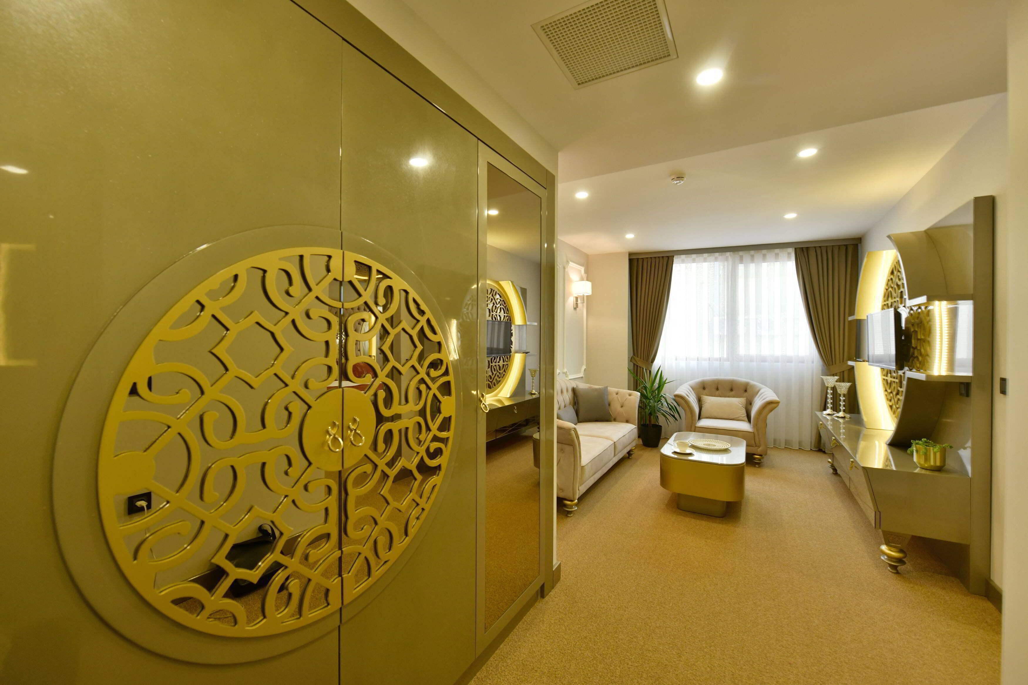A hotel room with a large decorative door, a sofa, a chair, a coffee table, and a mirror.