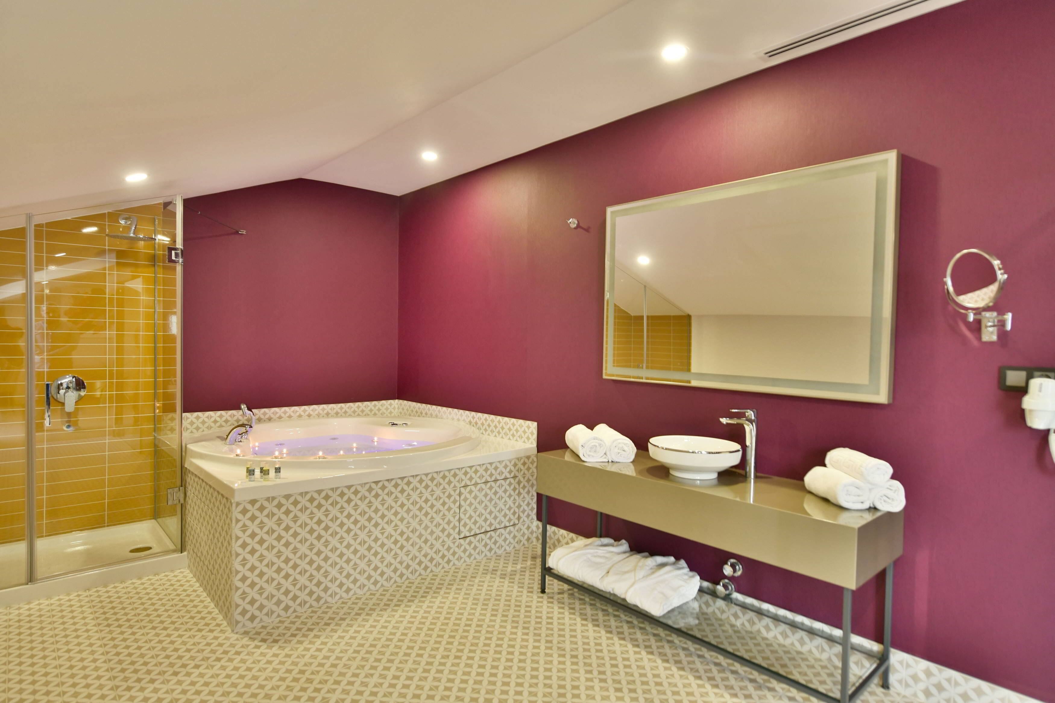 Un baño moderno con una bañera grande, un tocador con espejo y una zona de ducha.