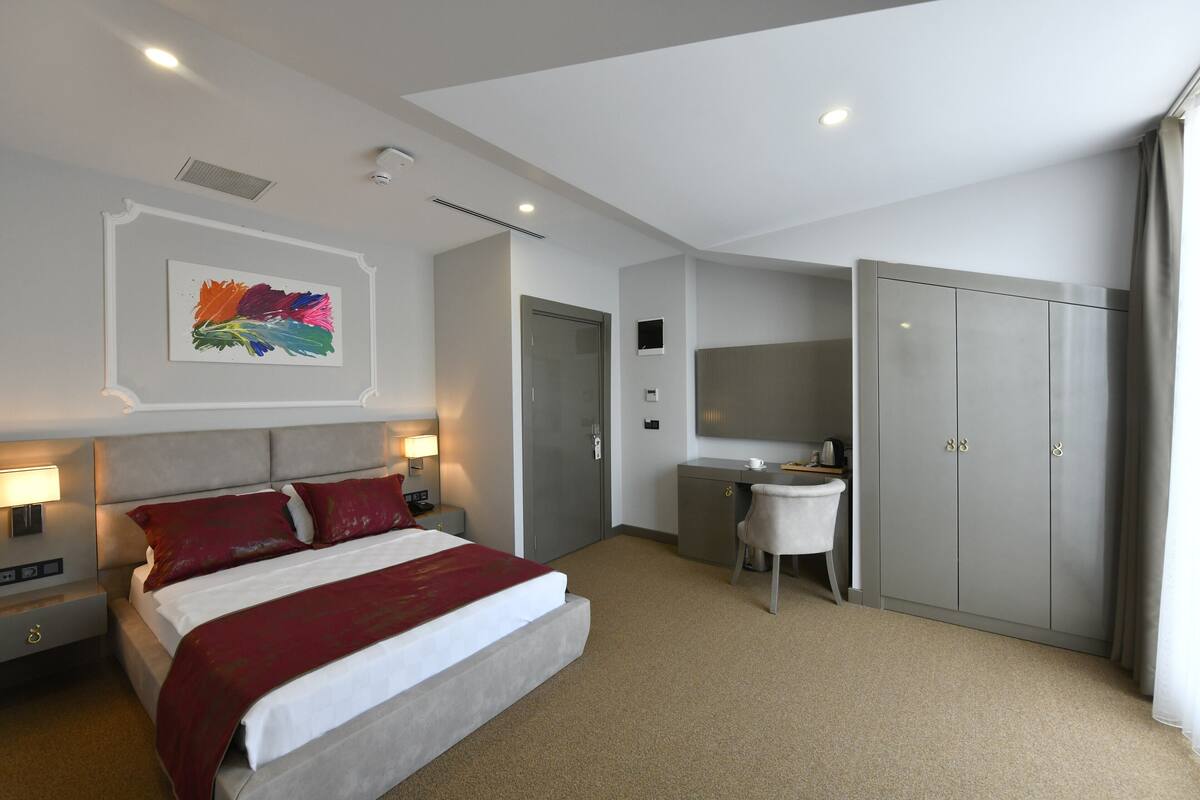 Een moderne hotelkamer met een groot bed, nachtkastjes, een bureau en een kledingkast.