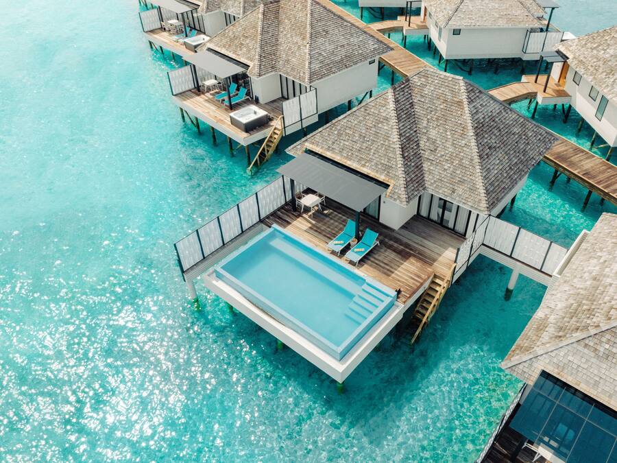 An aerial view of overwater bungalows with private pools and wooden walkways.