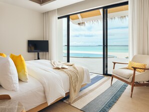 A bedroom with a large bed, a TV, and a view of the beach. - Nova Maldives (Vakaru)