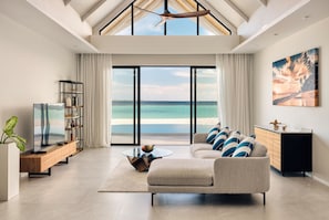 A spacious living room with a large window overlooking a beach, a ceiling fan, and a modern sofa. - Nova Maldives (Vakaru)