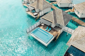 An aerial view of overwater bungalows with a swimming pool, wooden deck, and lounge chairs. - Nova Maldives (Vakaru)