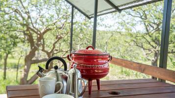 A wooden table with a red pot, a white mug, and a silver teapot.
