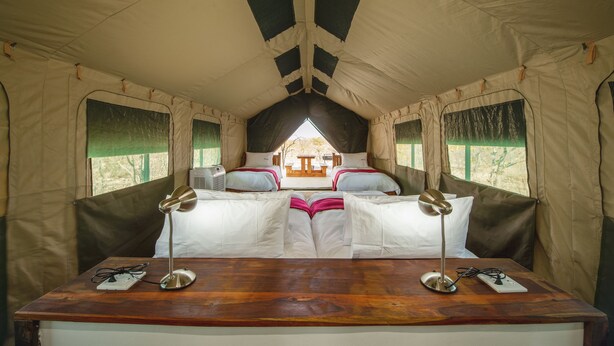 Una habitación con tienda de campaña, una cama, dos mesitas de noche y vistas al exterior.