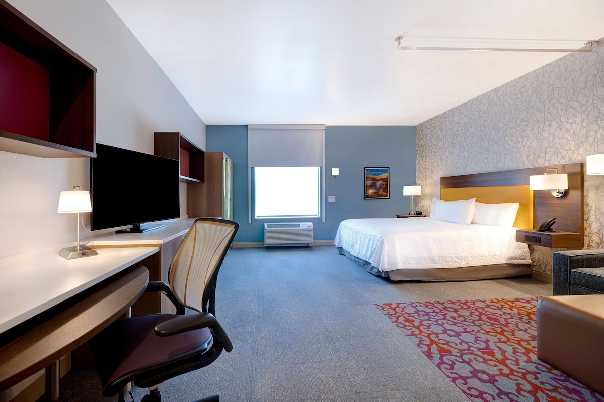 Habitación de hotel con escritorio, silla, cama y televisor.