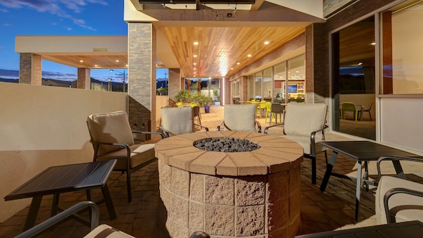 An outdoor patio area with a fire pit, seating, and a view of the interior restaurant. - Home2 Suites by Hilton Las Vegas Northwest (Las Vegas)