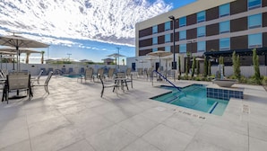 A rooftop pool area with lounge chairs and umbrellas, a swimming pool, and a modern building in the background. - Home2 Suites by Hilton Las Vegas Northwest (Las Vegas)