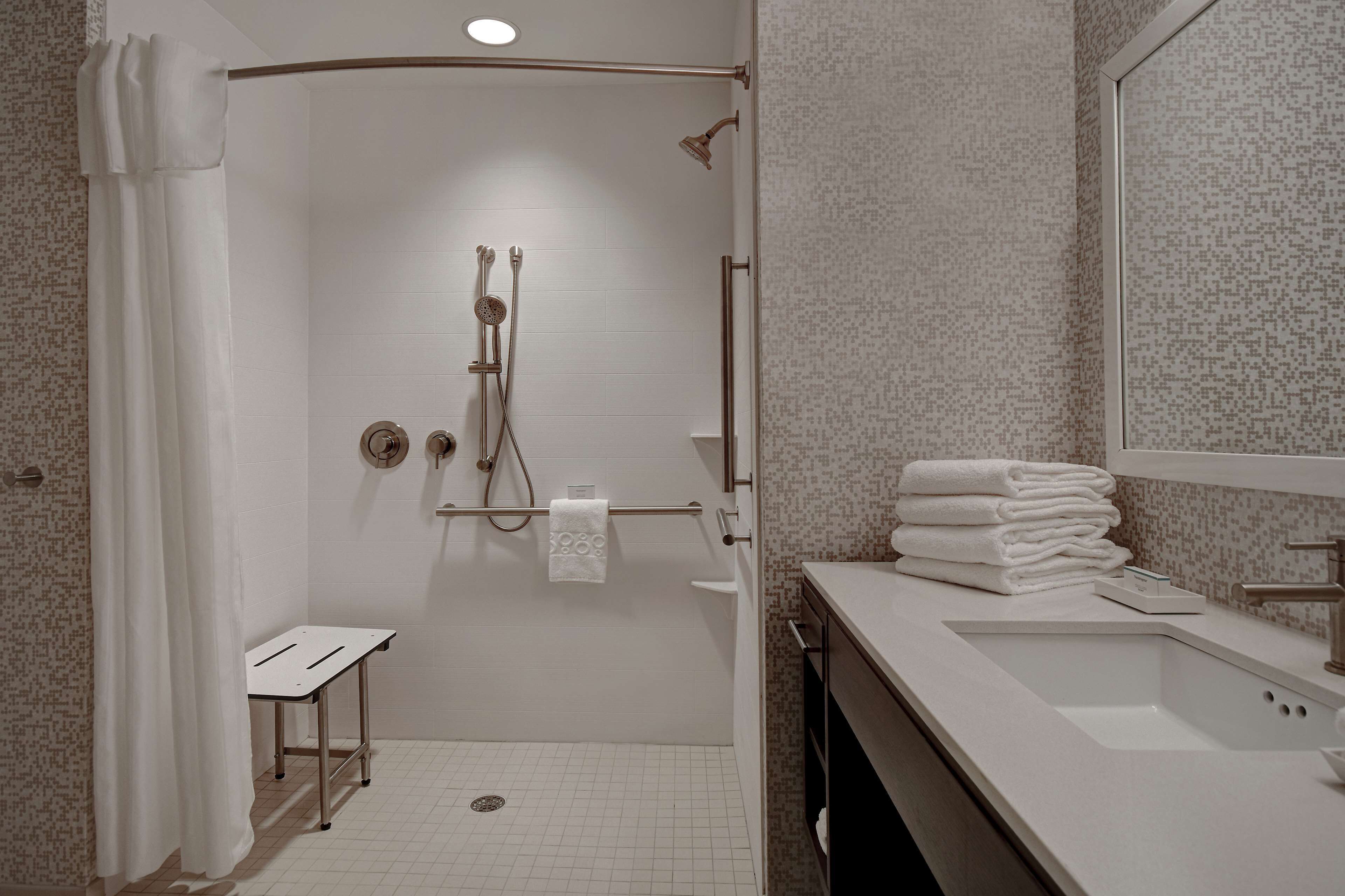 Een moderne badkamer met een douche, wastafel en spiegel.
