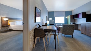 A hotel room with a bed, a desk with chairs, a TV, and a window. - Home2 Suites by Hilton Las Vegas Northwest (Las Vegas)