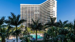 A high-rise hotel with multiple balconies, a swimming pool, and palm trees. - Beachfront 2BR/2BA condo in Marco Island with pool, WiFi, and coastal views. (Marco Island)