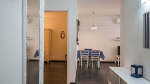 A modern interior with a dining area featuring a table and chairs, a white console table with a lantern, and a dark tiled floor. - Sciacchetrà Apartment with AC (Monterosso al Mare)