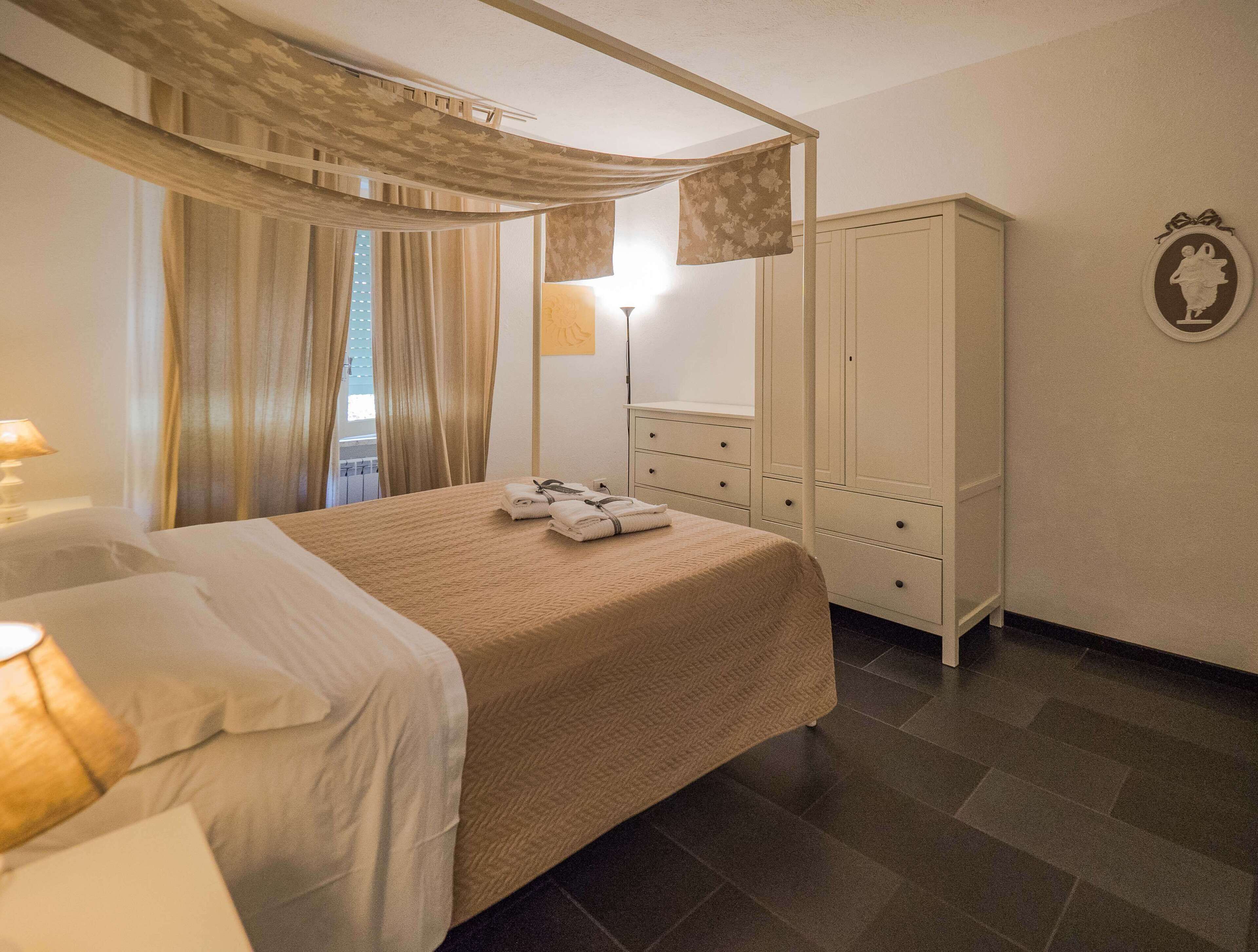 A neatly arranged bedroom with a bed, a wardrobe, and a bedside table with a lamp.