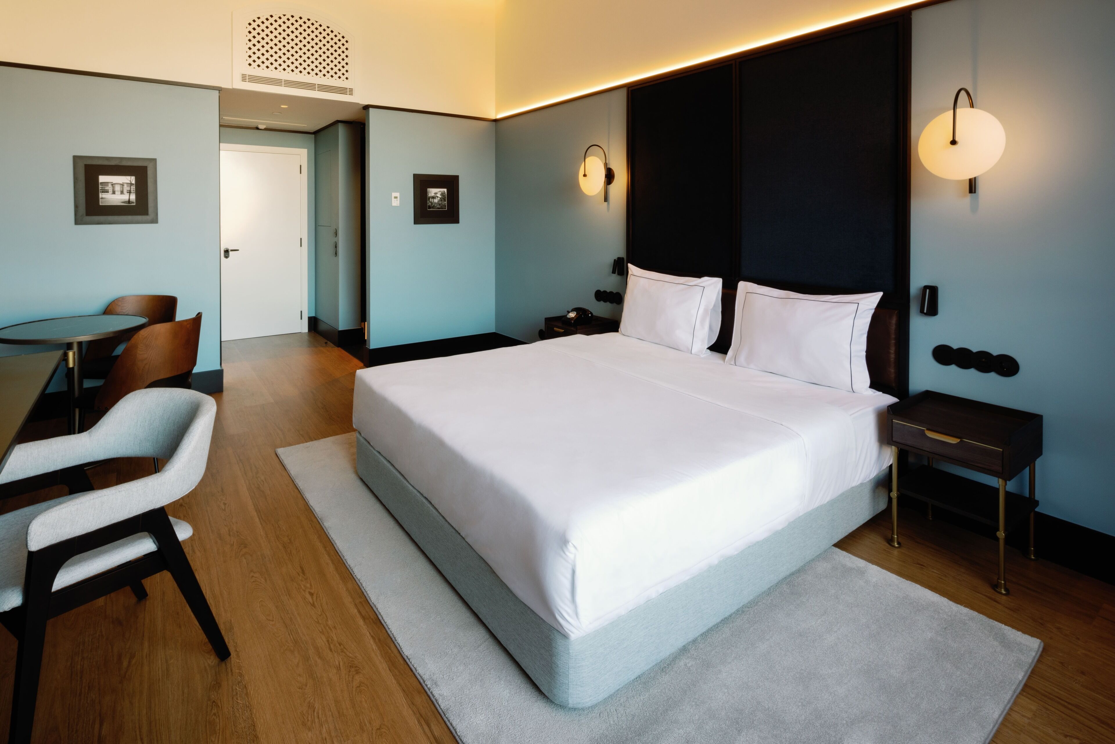 A modern hotel room with a large bed, a desk, and chairs.