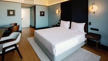 A modern hotel room with a large bed, a desk, and chairs.