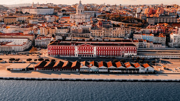 A coastal cityscape with a prominent red building with a white dome, surrounded by a mix of residential and commercial buildings. - The Editory Riverside Hotel, an Historic Hotel (Lisbon)