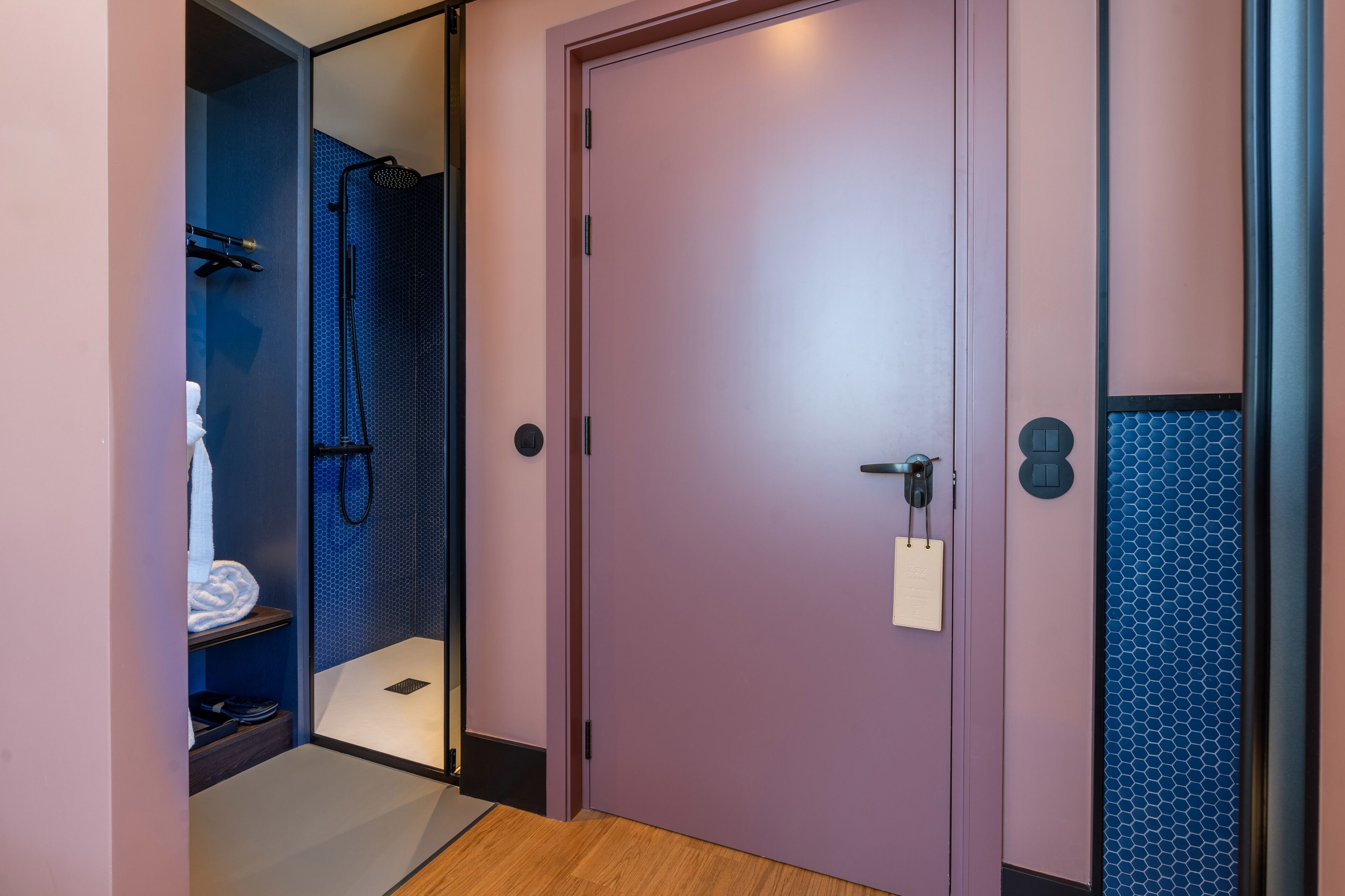 Ein modernes Badezimmer mit Dusche, Handtuchhalter und einer Tür mit Schloss und Schlüsselkartenfach.