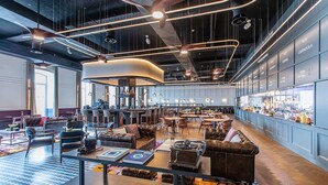 A spacious lobby with leather seating, a bar area, and a kitchen visible in the background. - The Editory Riverside Hotel, an Historic Hotel (Lisbon)