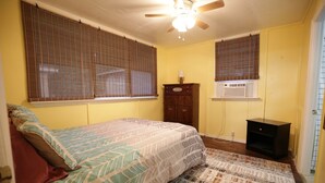 A bedroom with a bed, a ceiling fan, a window with blinds, a dresser, and a rug. - Bee Our Guest | East Pensacola Heights Rental Near Downtown Pensacola Beach (Pensacola)