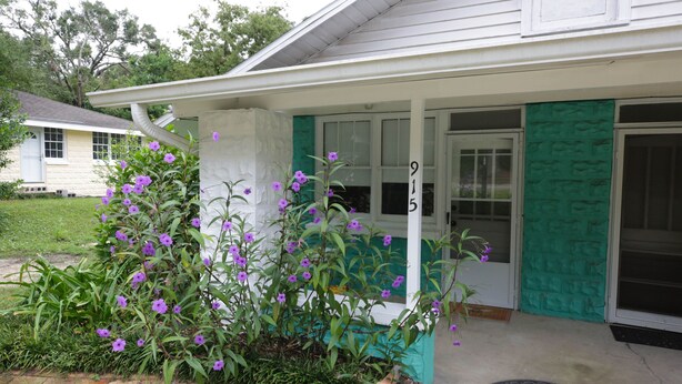 A house with a porch, a green door, and a number '9' on the door. - Bee Our Guest | East Pensacola Heights Rental Near Downtown Pensacola Beach (Pensacola)