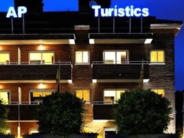 Un edificio de varios pisos con letreros iluminados que dicen "AP" y "Turistics".
