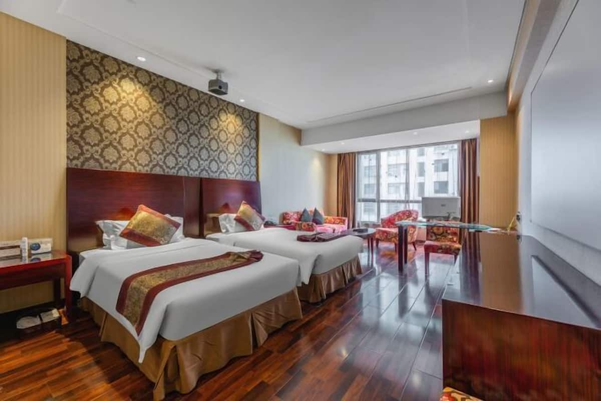 Une chambre d’hôtel avec deux lits, un bureau, une chaise et une grande fenêtre.