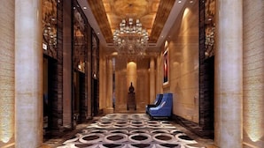 A grand hallway with marble flooring, a large chandelier, and blue seating on the right. - Howard Johnson Park Plaza Hotel (Jingshan Railway Station Inn) (Jingshan)