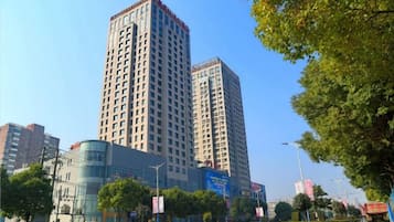 A high-rise building with multiple floors, surrounded by trees and a clear sky.