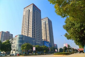 A high-rise building with multiple floors, surrounded by trees and a clear sky. - Howard Johnson Park Plaza Hotel (Jingshan Railway Station Inn) (Jingshan)