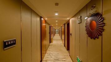 Un pasillo de hotel largo, con puertas a ambos lados y un cartel de números a la izquierda.