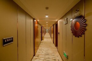 Un pasillo de hotel largo, con puertas a ambos lados y un cartel de números a la izquierda.