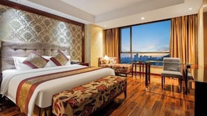 A hotel room with a large bed, a sofa, a desk, and a view of the city. - Howard Johnson Park Plaza Hotel (Jingshan Railway Station Inn) (Jingshan)