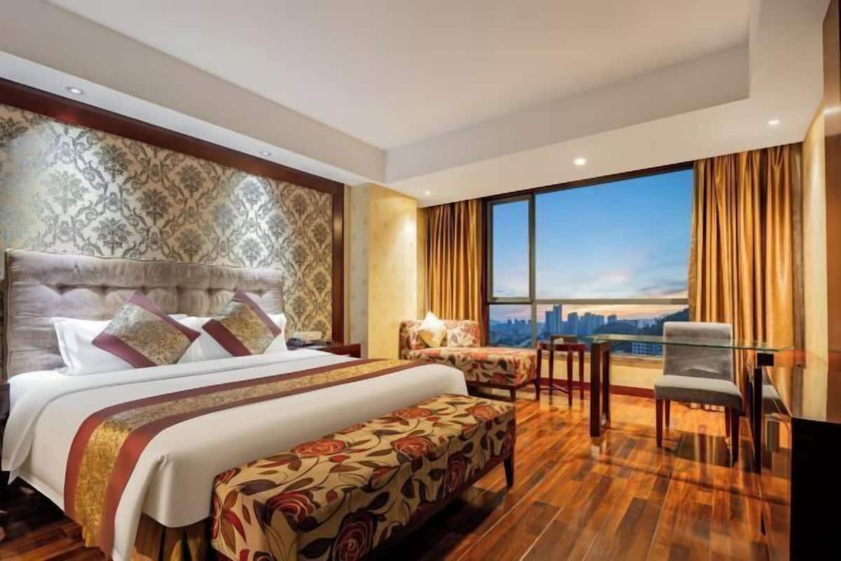 Une chambre d’hôtel avec un grand lit, un canapé, un bureau et une vue sur la ville.