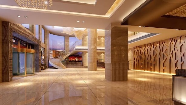 A spacious lobby with a high ceiling, a staircase leading to an upper level, and a decorative wall with geometric patterns. - Howard Johnson Park Plaza Hotel (Jingshan Railway Station Inn) (Jingshan)