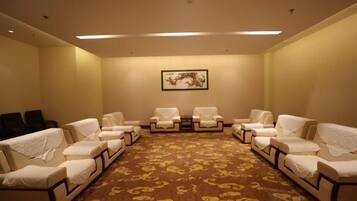 A room with a carpeted floor, a framed picture on the wall, and multiple chairs.