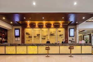 A hotel reception area with a marble counter, wooden ceiling, and a digital screen. - Howard Johnson Park Plaza Hotel (Jingshan Railway Station Inn) (Jingshan)