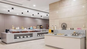 A modern hotel reception area with a marble counter, a coffee machine, and a decorative wheel. - Howard Johnson Park Plaza Hotel (Jingshan Railway Station Inn) (Jingshan)