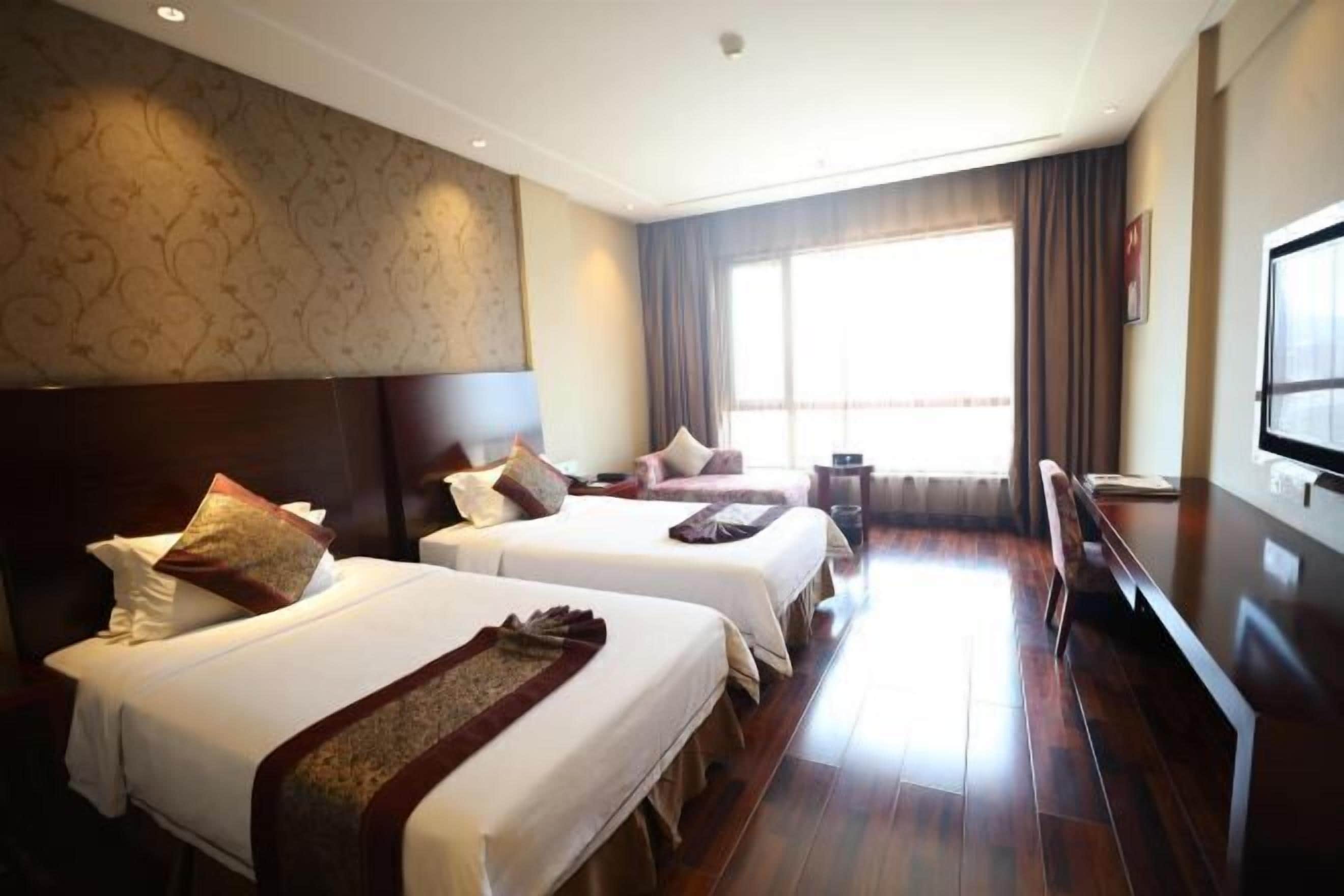 A hotel room with two beds, a large window, and a flat-screen TV.