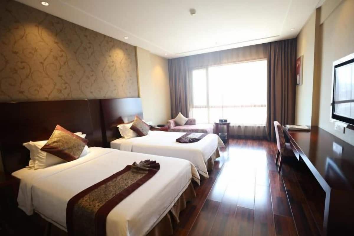 A hotel room with two beds, a large window, and a flat-screen TV.