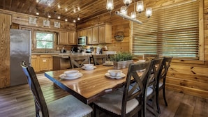 A wooden interior with a dining table set for four, surrounded by wooden chairs. - Cozy Bear Lodge-peaceful, easy access, beautiful view (Sevierville)