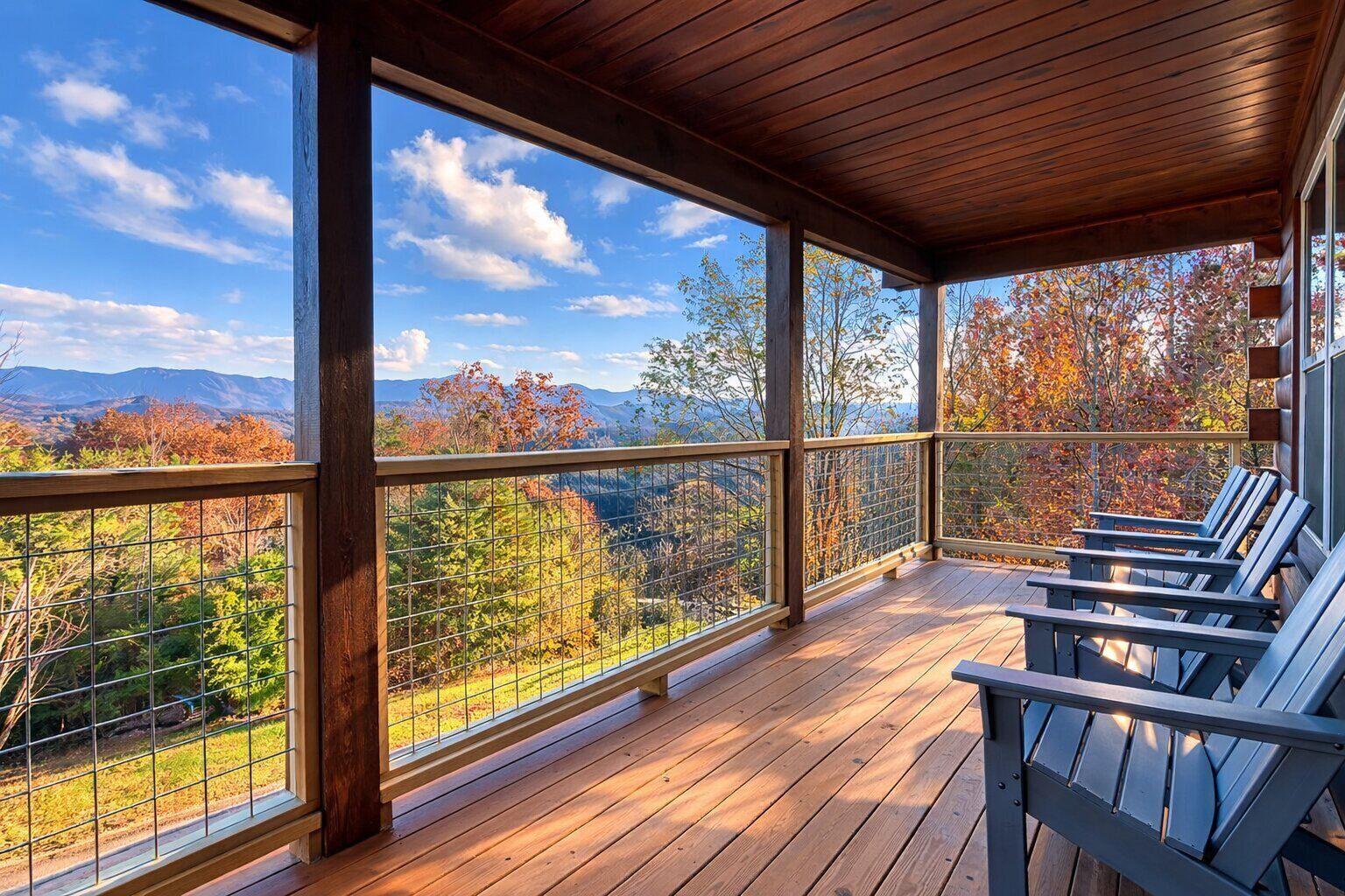 Une véranda couverte avec un plancher en bois, des rampes en métal et des fauteuils Adirondack.