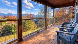 A covered porch with wooden flooring, metal railings, and Adirondack chairs. - Cozy Bear Lodge-peaceful, easy access, beautiful view (Sevierville)