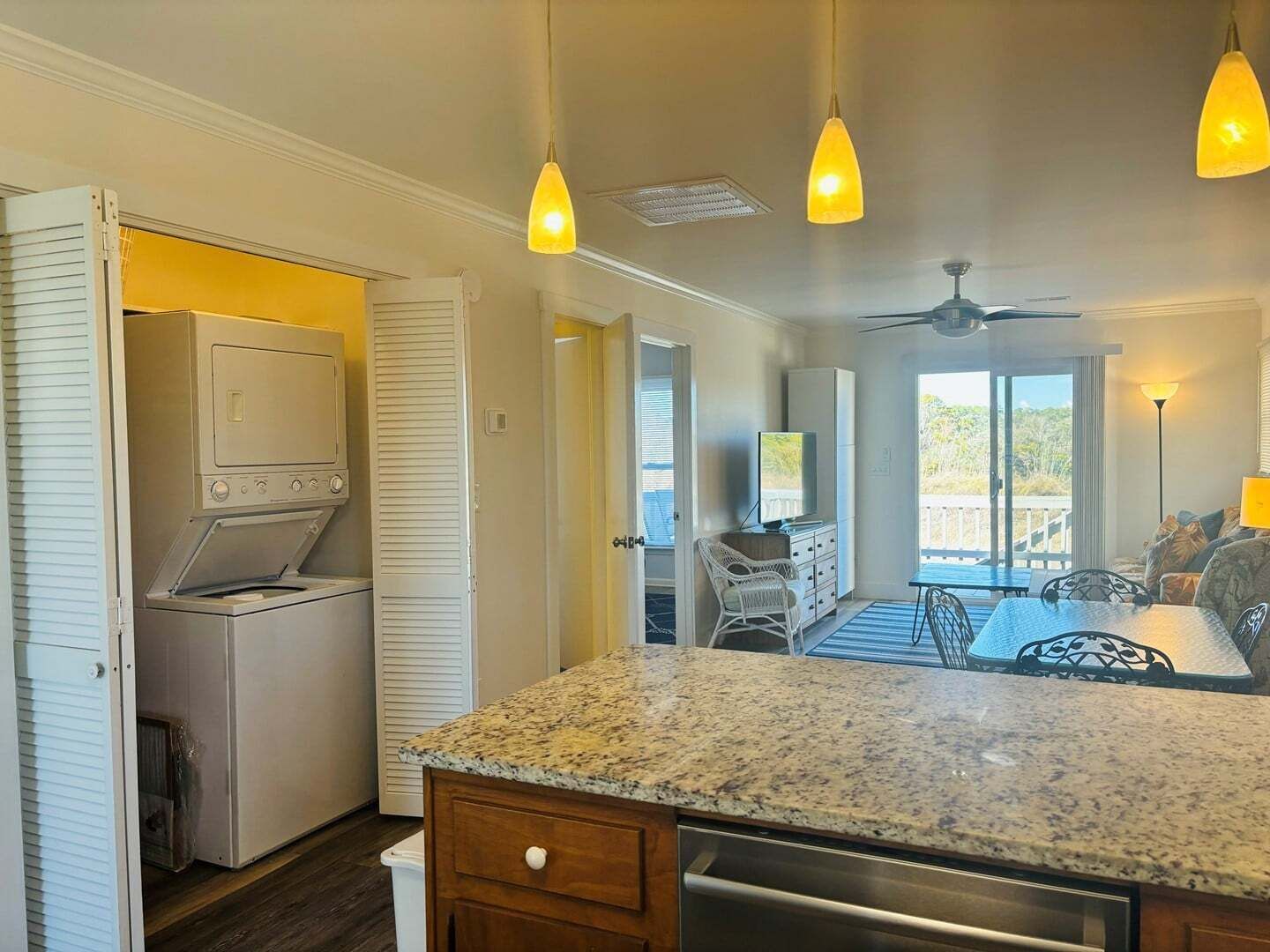 Una cocina con lavadora y secadora integradas, encimera de granito y zona de comedor con mesa y sillas.