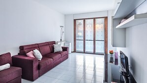 Un saló modern amb un sofà, una televisió de pantalla plana i una taula petita amb objectes decoratius.