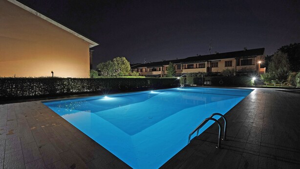 Una piscina amb una superfície blava i cristal·lina, envoltada per un paviment i un petit setill.