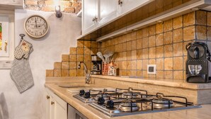Una cocina con estufa a gas, un reloj y una cafetera.